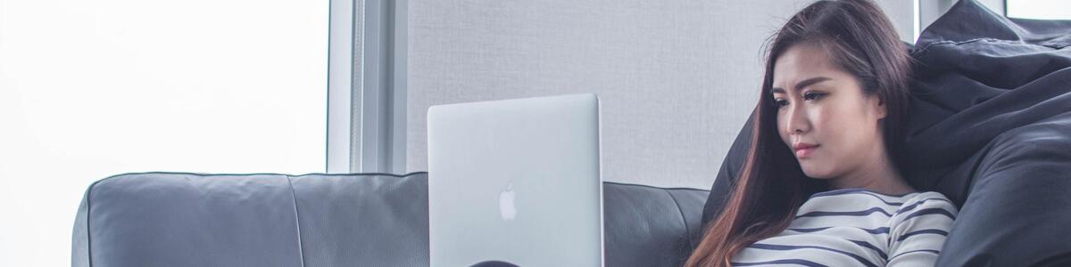 Pige der sidder med sin pc i en sofa