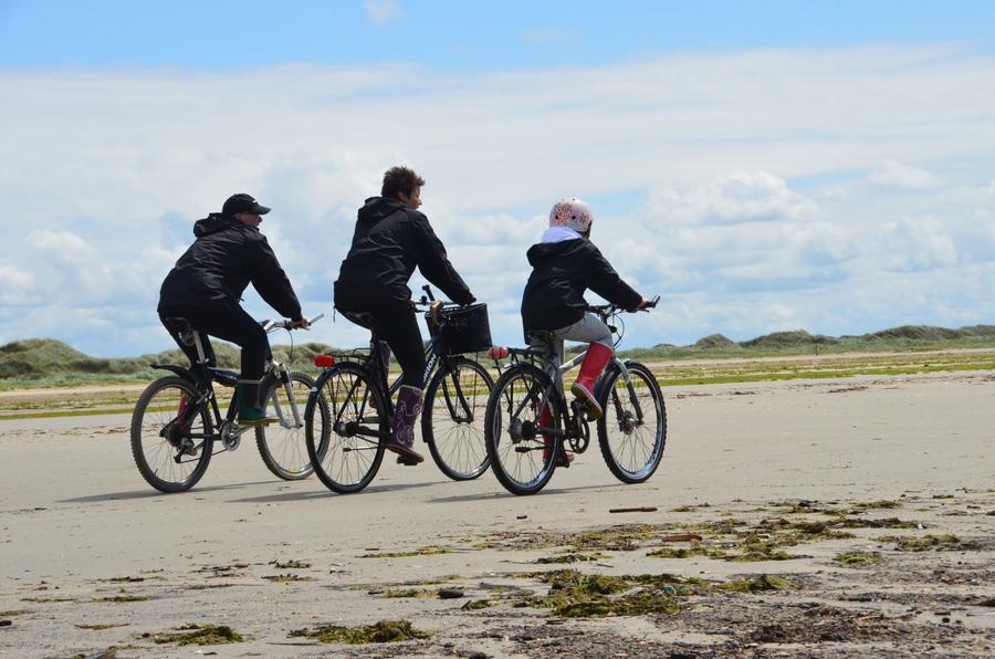 Tre cyklister på en strand