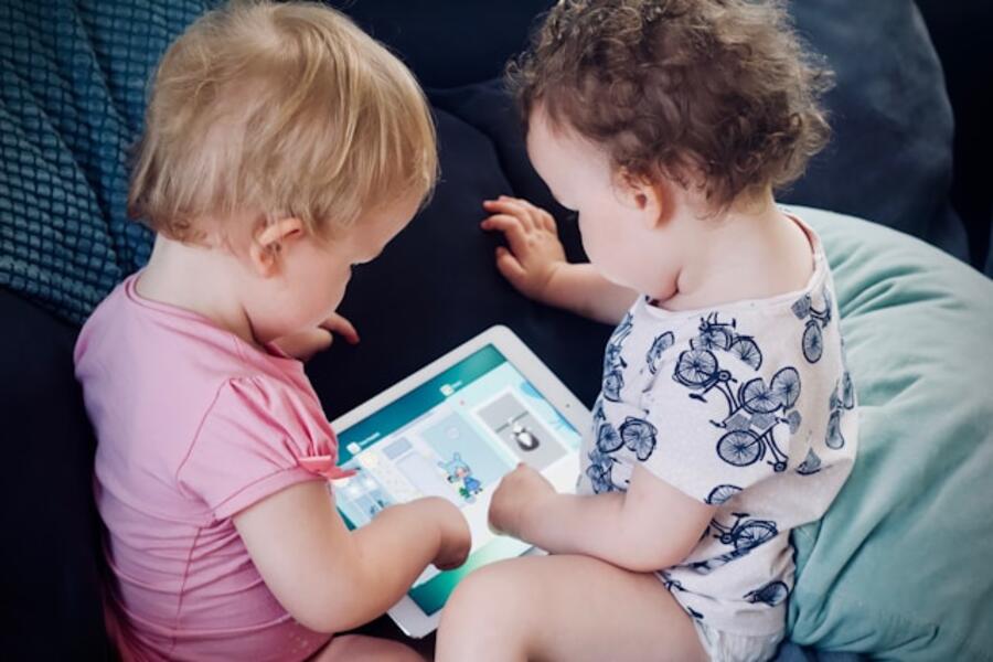Photo by Jelleke Vanooteghem on Unsplash To små børn der kigger på en tablet